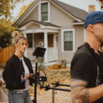 two caucasian blonde fitness video production managers overseeing a shoot with two men in the forefront assisting