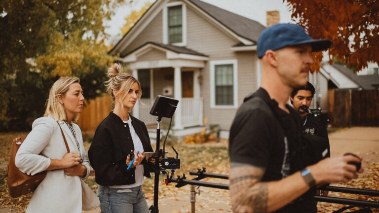 two caucasian blonde fitness video production managers overseeing a shoot with two men in the forefront assisting